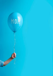 Child&rsquo;s hand holding a balloon with « MOM » written on it